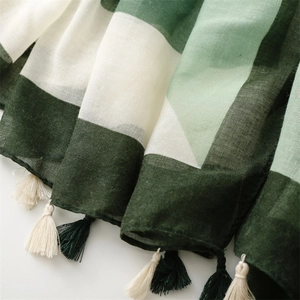 Detail of cotton-linen scarf with green geometric pattern and handmade fringe edges