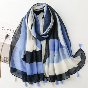 Detail of color-block scarf with geometric blue patterns and fringe on white background