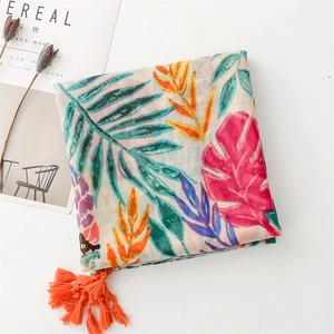Detail of tropical leaf print scarf with bright orange tassels and lightweight fabric