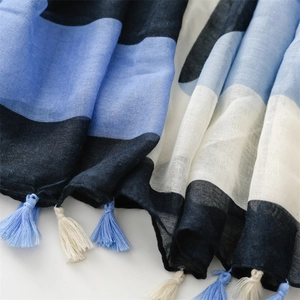 Detail of color-block scarf featuring light blue and navy cotton-linen texture with tassels