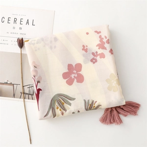 Détail de l'écharpe effet lin avec pompons roses élégants et motifs floraux abstraits