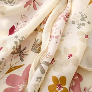 Détail macro de l'écharpe beige effet lin avec imprimé floral vintage et texture