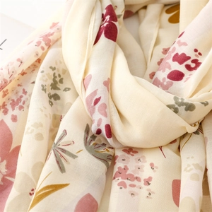 Gros plan des motifs floraux sur une écharpe crème douce avec texture aspect lin