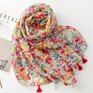 Close-up of floral print scarf with soft fringe tassels on a minimalist background