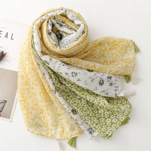 Detail of floral print scarf with soft yellow and green patterns and tassel fringe edge