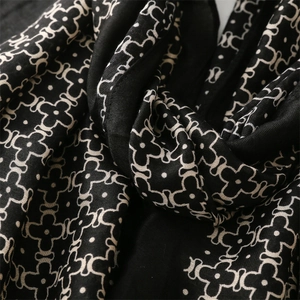 Close-up of black cotton-linen scarf with white clover floral pattern and soft texture