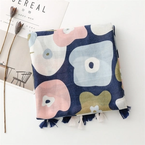 Dettaglio sciarpa in cotone-lino blu navy con stampe floreali e nappe su sfondo bianco