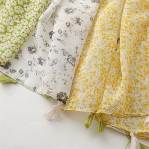 Detail of floral printed scarves with tassel fringe in cotton and linen texture
