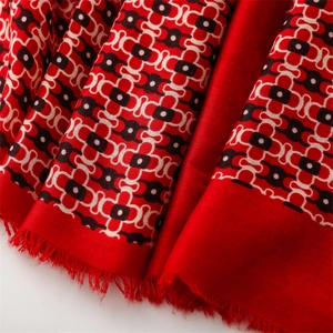 Macro detail of red geometric pattern scarf showing soft fabric texture and fine fringe edge