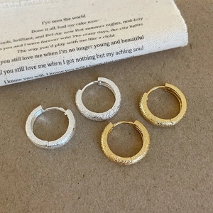 Matte geometric hoop earrings in gold and silver set on vintage background