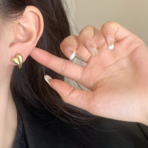 Elegant matte gold heart-shaped stud earrings worn by model for a minimalist fashion look
