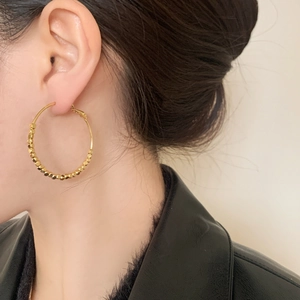Grandi orecchini a cerchio dorati con perline metalliche testurizzate per un look moderno
