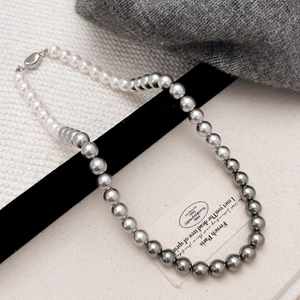 Detailed view of handmade gradient pearl necklace transition from white to silver on velvet