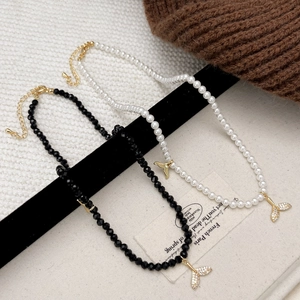 Elegant mermaid tail pendant necklace featuring black beads and pearls with sparkling crystals