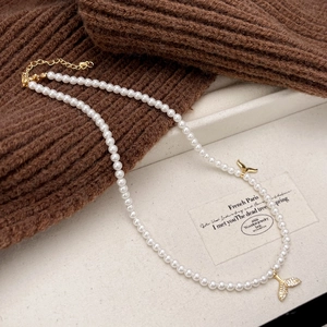 Detail of dual mermaid tail pendant with pearls and micro-pave crystals on gold necklace