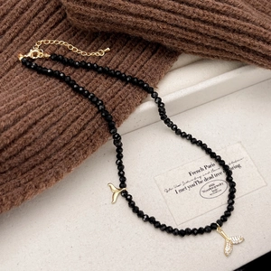 Detail of black faceted bead necklace with sparkling mermaid tail pendants and gold chain