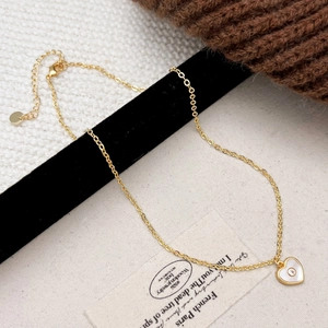 Détail du pendentif cœur doré avec incrustation de coquillage et zircon sur tissu