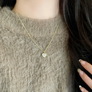 Collier élégant doré avec pendentif cœur en nacre et zircon porté sur une maille marron