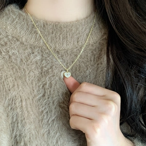 Collier avec pendentif cœur doré, nacre blanche et cristal brillant sur un mannequin