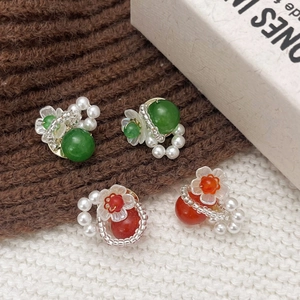 Elegant floral pearl stud earrings with green and orange gemstones on knit fabric