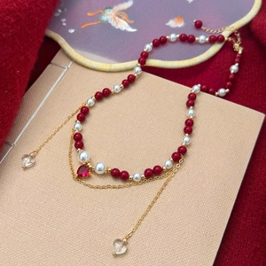 Elegant beaded necklace with red and pearl beads, heart pendant and gold fringe