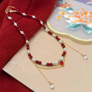 Macro detail of red beads and white pearls necklace with a heart pendant and gold chain