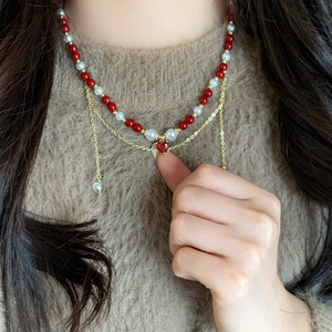 Double-layer pearl necklace with red heart pendant and gold chain on model