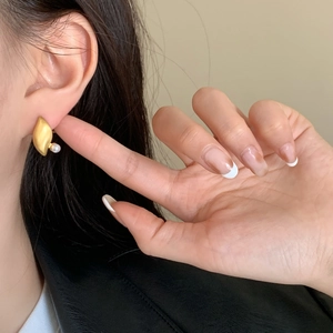 Minimalist gold leaf earring with pearl accent shown on ear in a natural style