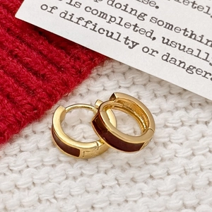 Élégantes créoles plaquées or avec émail rouge sur un fond en tricot blanc pur
