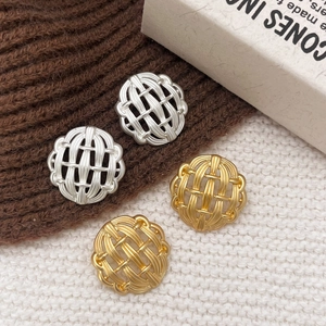 Goldene und silberne gewebte geometrische Ohrstecker auf Strickhintergrund
