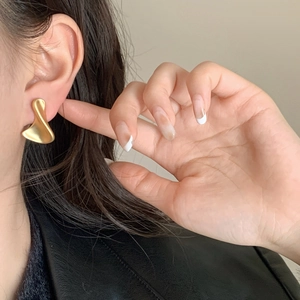 Golden irregular wave earrings with matte brushed finish shown on a female model