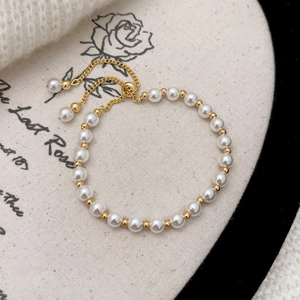Detail of pearl bracelet with golden adjustable slide clasp on vintage rose cloth