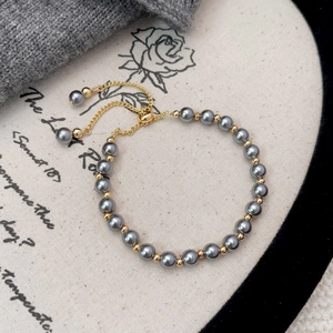 Detailed shot of dark grey pearl bracelet with gold metal beads and adjustable slider chain