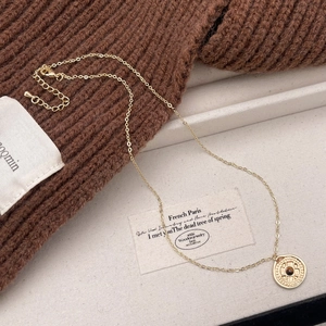 Detail of vintage gold round pendant with tiger eye stone on a textured display