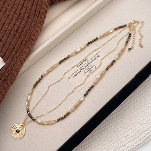 Detail of vintage layered tiger eye stone and shell beaded necklace with gold pendant