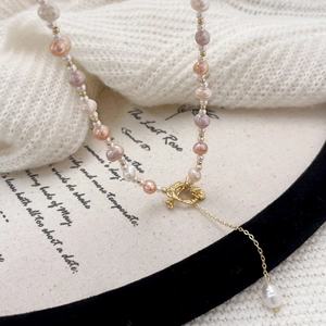 Elegant natural freshwater pearl necklace with gold flower clasp on a white knit sweater