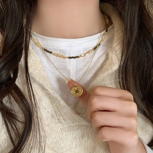 Detail of layered vintage tiger eye necklace with beaded chain and relief coin pendant