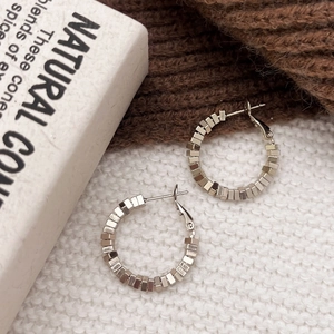 Silver textured hoop earrings with a unique square bead design on knitted background