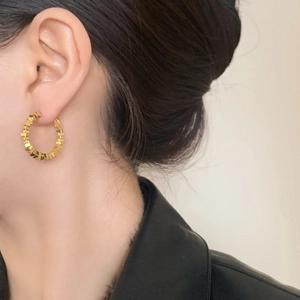 Detail of geometric gold hoop earrings with textured crushed silver design on ear
