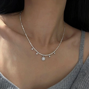 Close-up of silver-toned pearl necklace with crystal star and round pendants on neck
