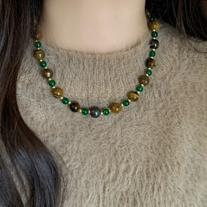 Vintage necklace with tiger eye stones and green beads on a beige sweater