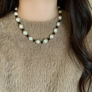 Collier élégant en perles et œil de tigre porté sur un pull en peluche de qualité
