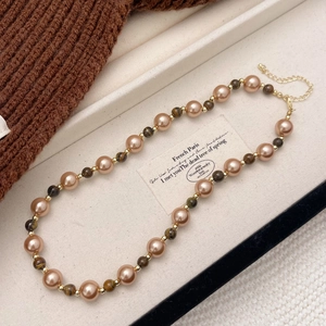 Detail of beaded necklace with tiger eye stones and brown pearls on knit background