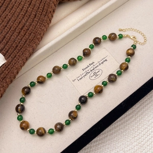 Close-up of vintage brown tiger eye stone beads and green chalcedony pearls necklace