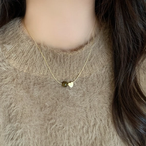 French vintage tiger eye beaded necklace with a gold heart pendant on beige sweater