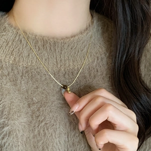 Detailed view of a gold beaded necklace with a brown tiger eye stone and heart pendant