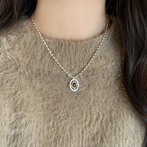 Tiger eye stone oval pendant necklace on a brown sweater background, elegant retro style