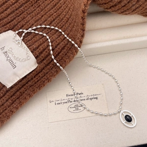 Detail of vintage silver beaded chain necklace with an oval black onyx gemstone pendant