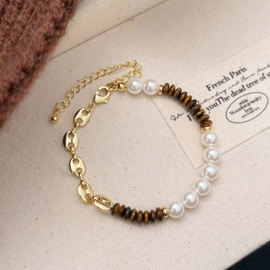 Detail view of tiger eye beads and pearl links with gold-plated pig nose chain bracelet