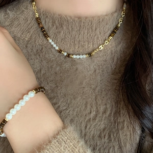 Tiger eye and pearl beaded necklace set with golden buckle on brown knit sweater